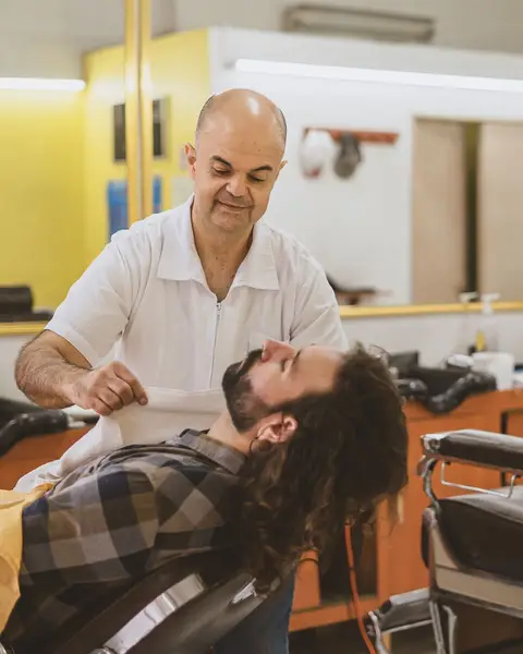 Barbeiro fazendo a barba de um cliente