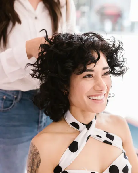 Cabeleireira finalizando o cabelo de uma cliente